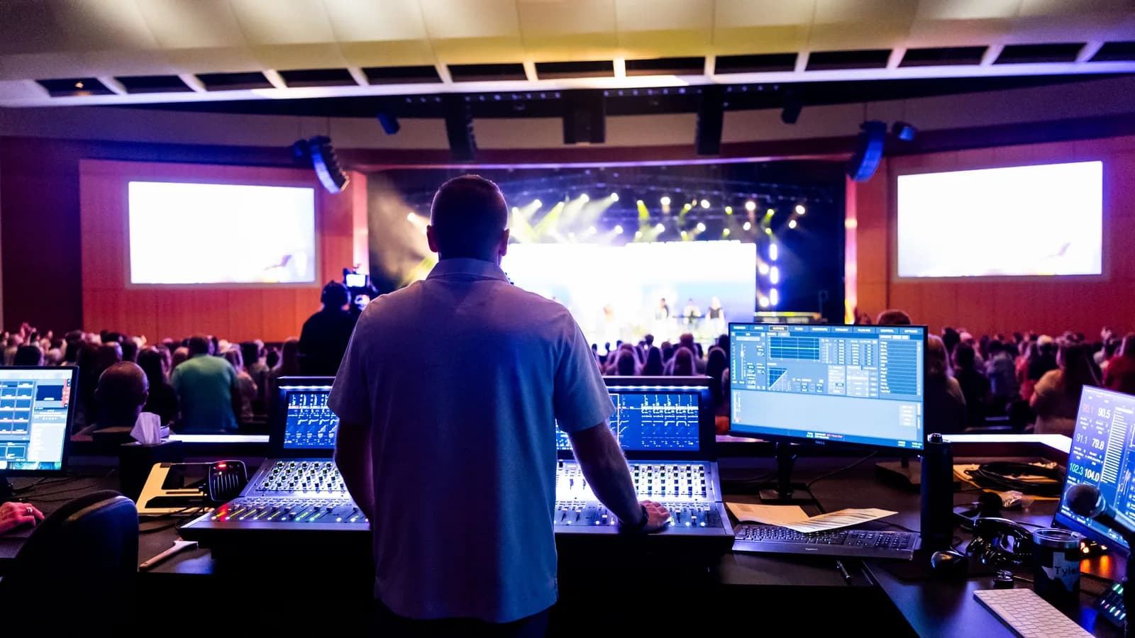 Church production operator at a media booth during a live service